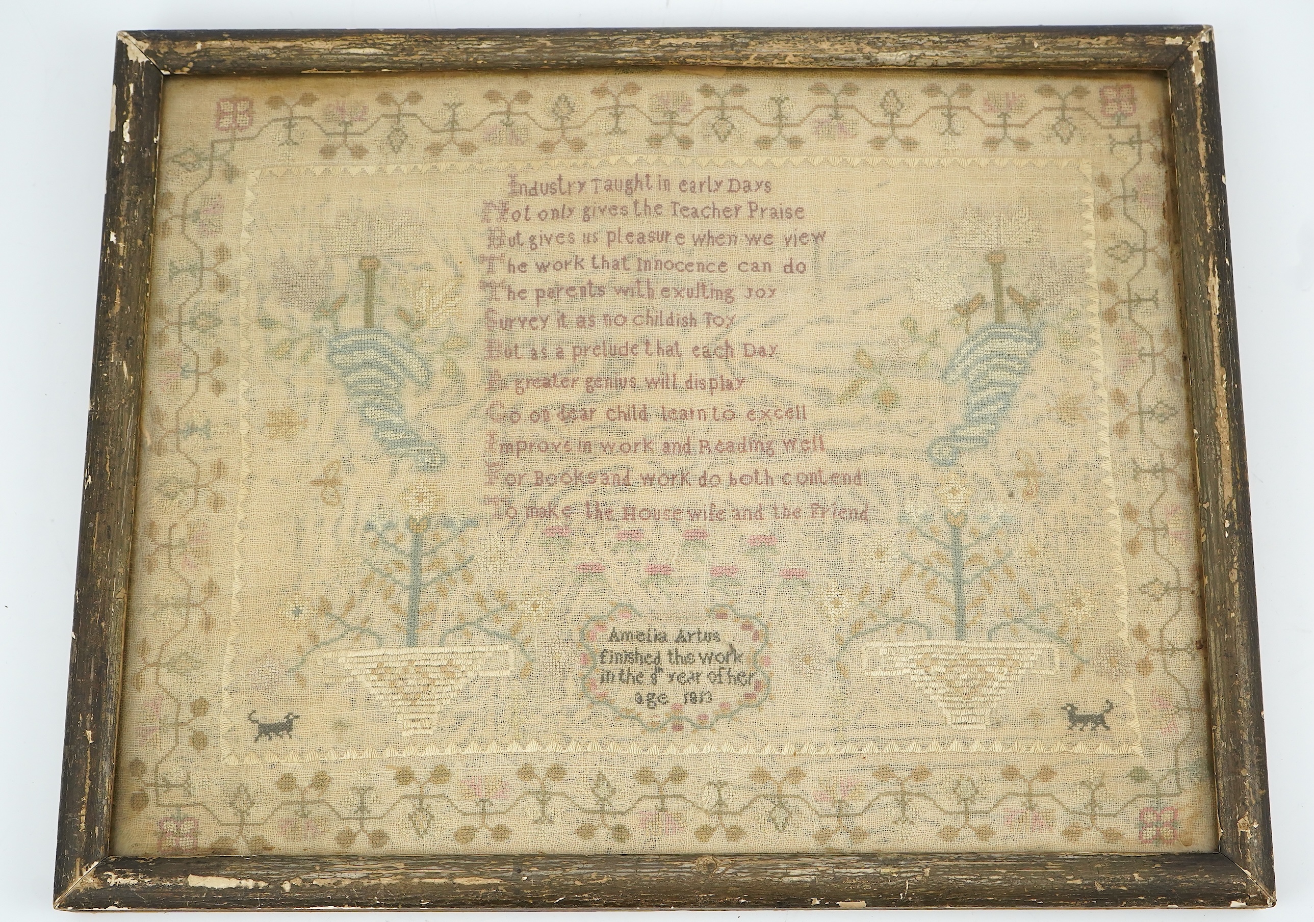 A gilt framed finely worked Regency gauze sampler, by Amelia Artus, aged 8 years, dated 1813, worked on fine gauze with coloured silk threads, with a large central panel having a long verse, two motifs of cornucopia, pot